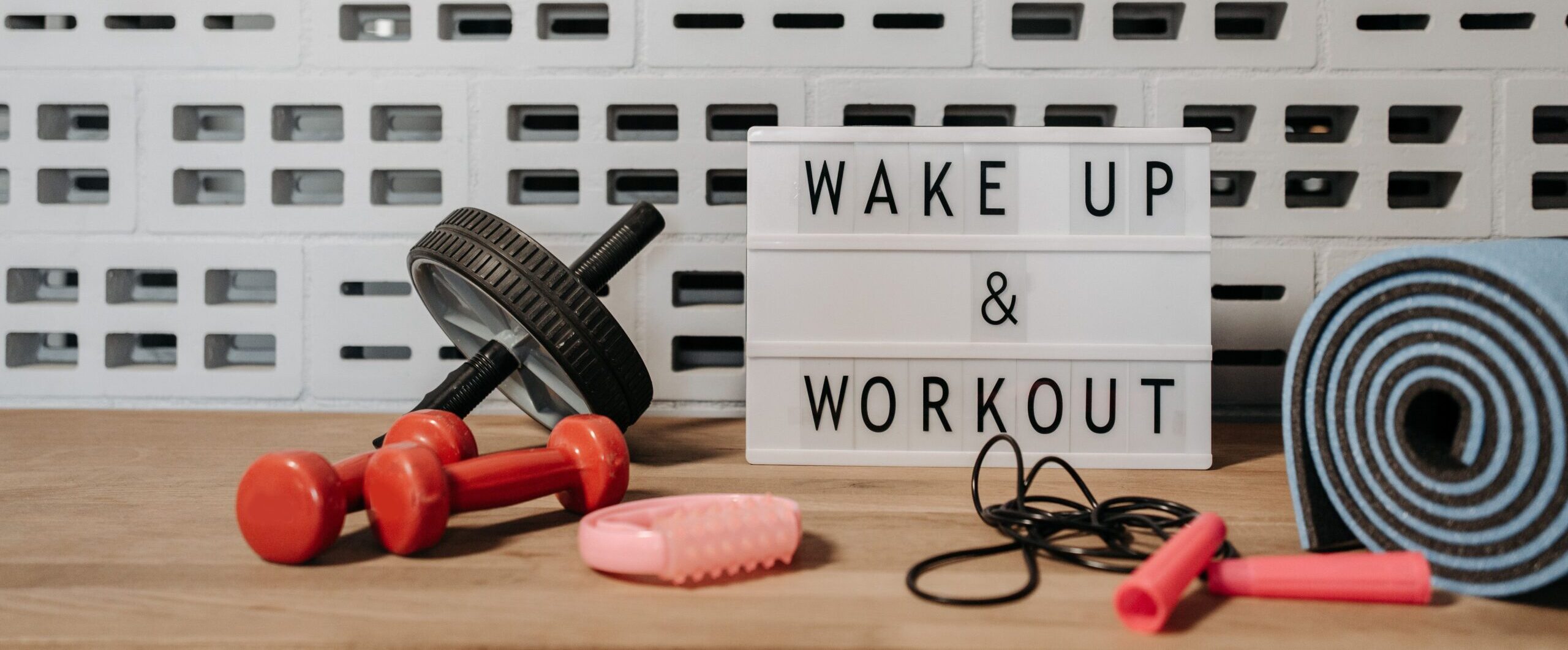 Fitness gear and motivational sign in home gym setup against a brick wall.